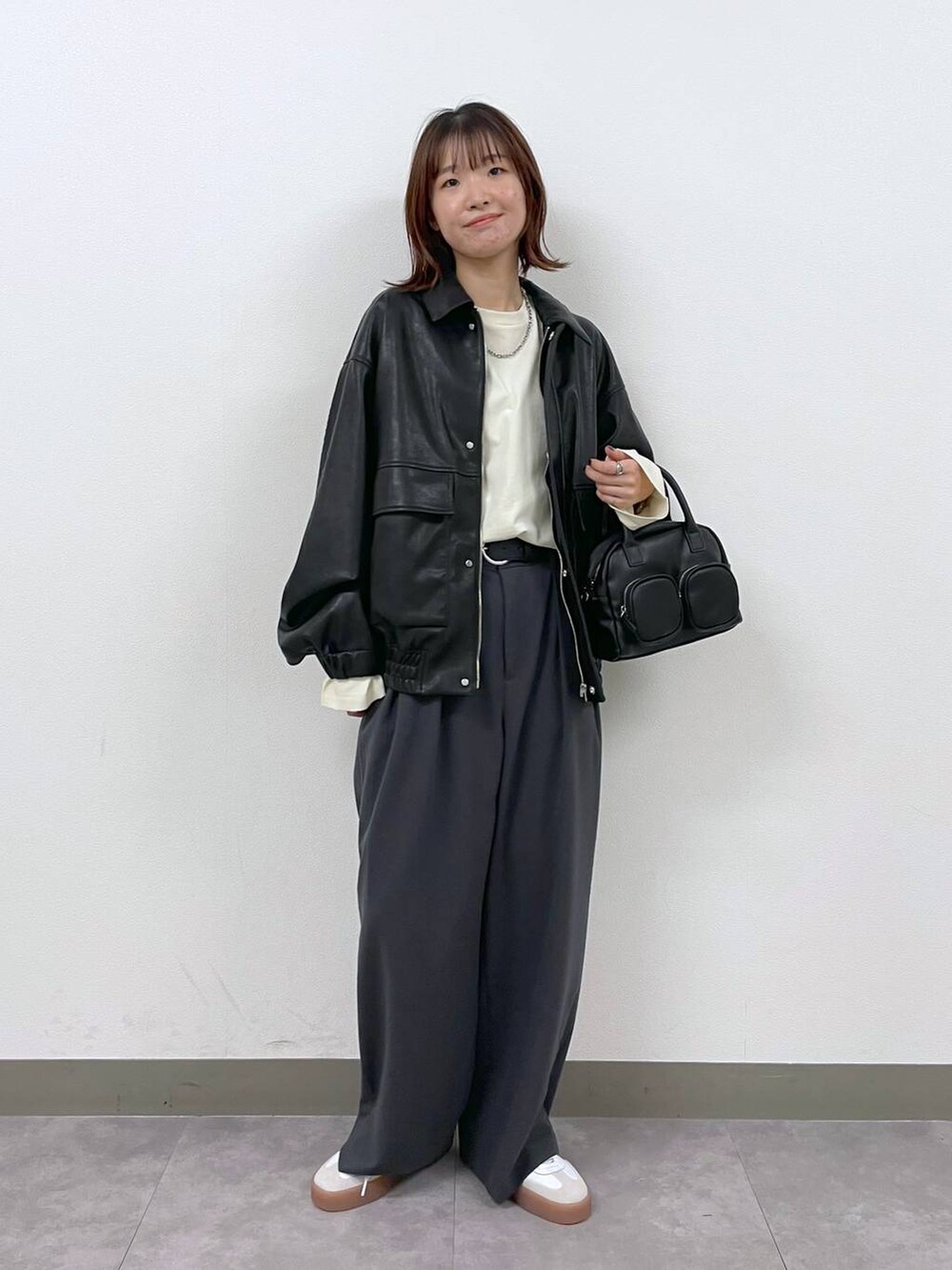 ブラック系のブルゾン、ブラック系のショルダーバッグ、グレー系のスラックスを着用したレディースの秋コーディネートの5枚目の写真