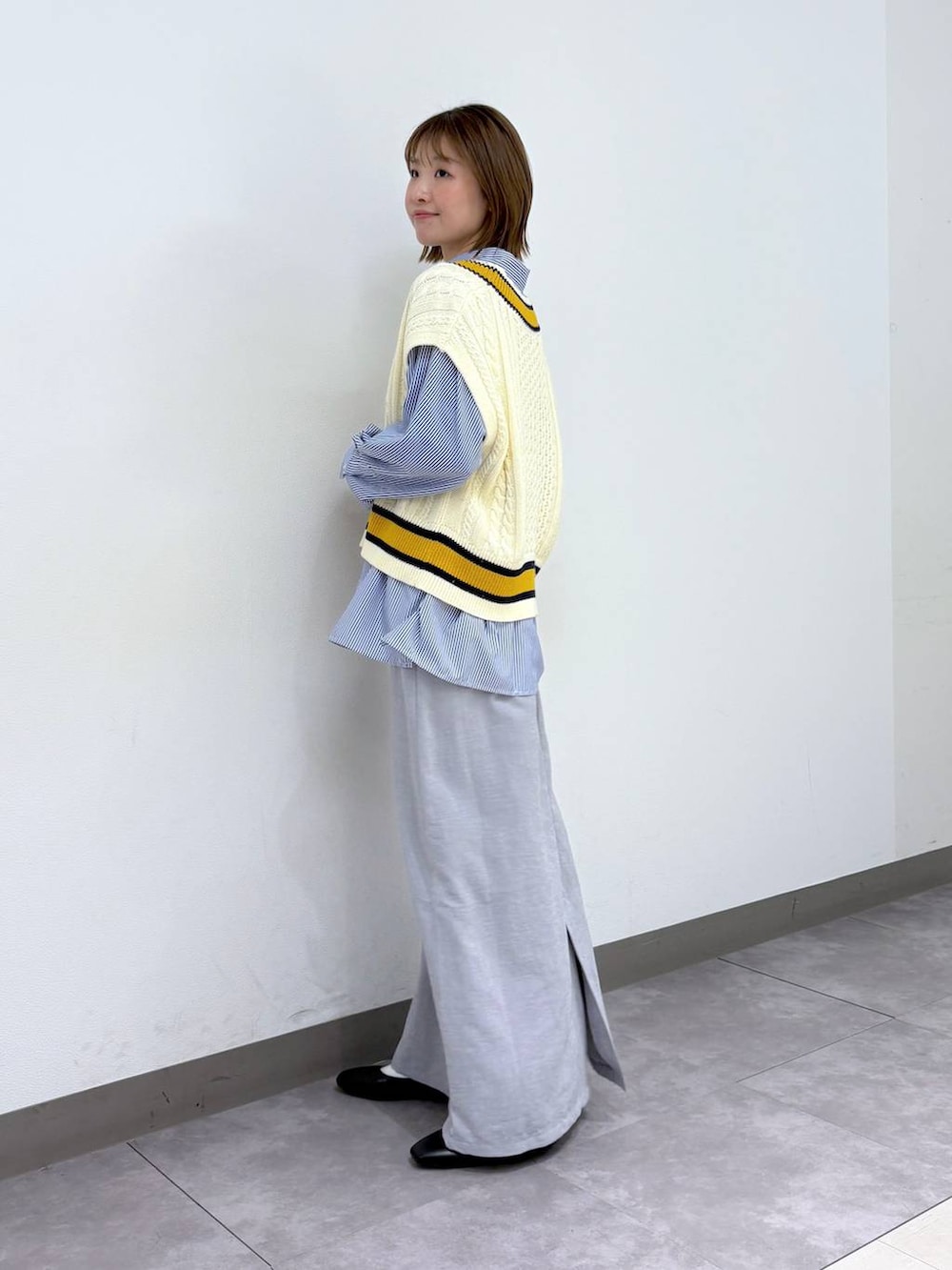 ブラック系のパンプス、ブルー系のシャツ/ブラウス、ホワイト系のベストを着用したレディースの春コーディネートの3枚目の写真