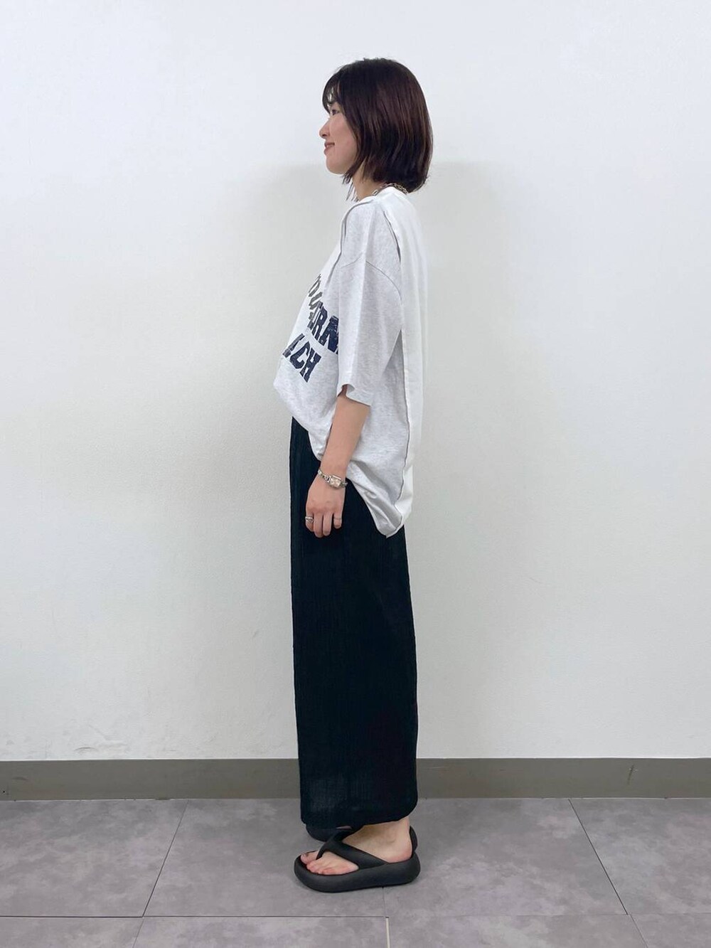 ブラック系のスカート、ホワイト系のTシャツ/カットソー、その他のネックレスを着用したレディースの夏コーディネートの3枚目の写真