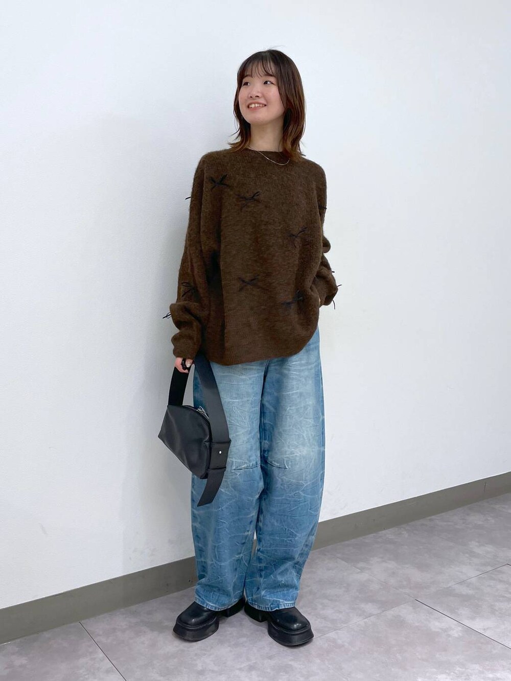 ブラック系のブーツ、ブラック系のショルダーバッグ、ブルー系のデニムパンツを着用したレディースの冬コーディネートの5枚目の写真