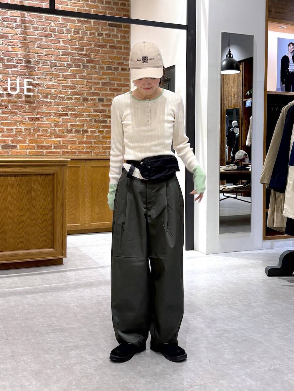 ブラック系のボディバッグ/ウエストポーチ、ホワイト系のニット/セーター、ベージュ系のキャップを着用したレディースの春コーディネートの3枚目の写真