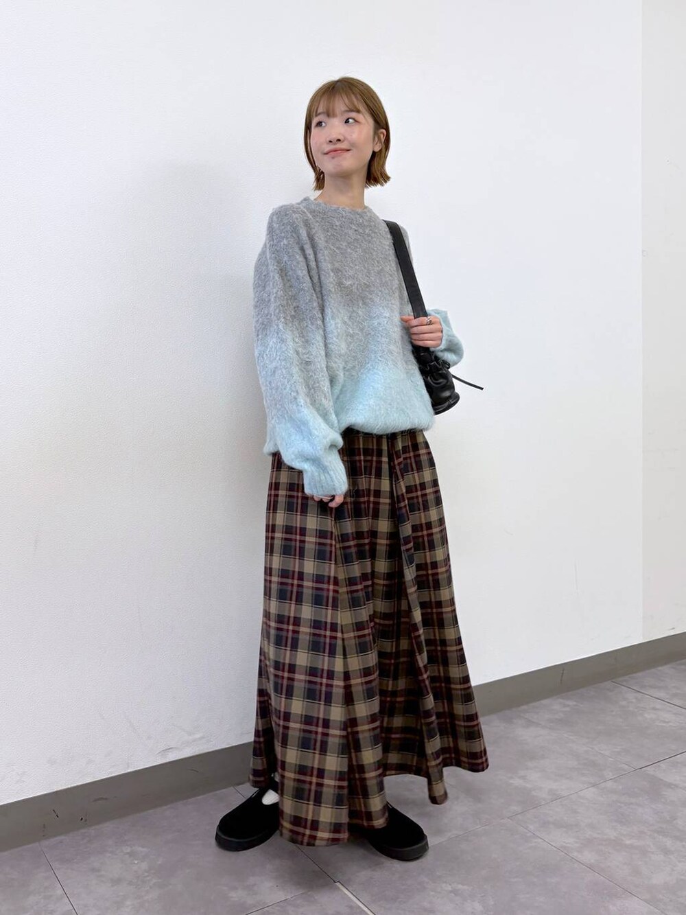 ブラック系のショルダーバッグ、レッド系のスカート、グレー系のニット/セーターを着用したレディースの秋コーディネートの4枚目の写真