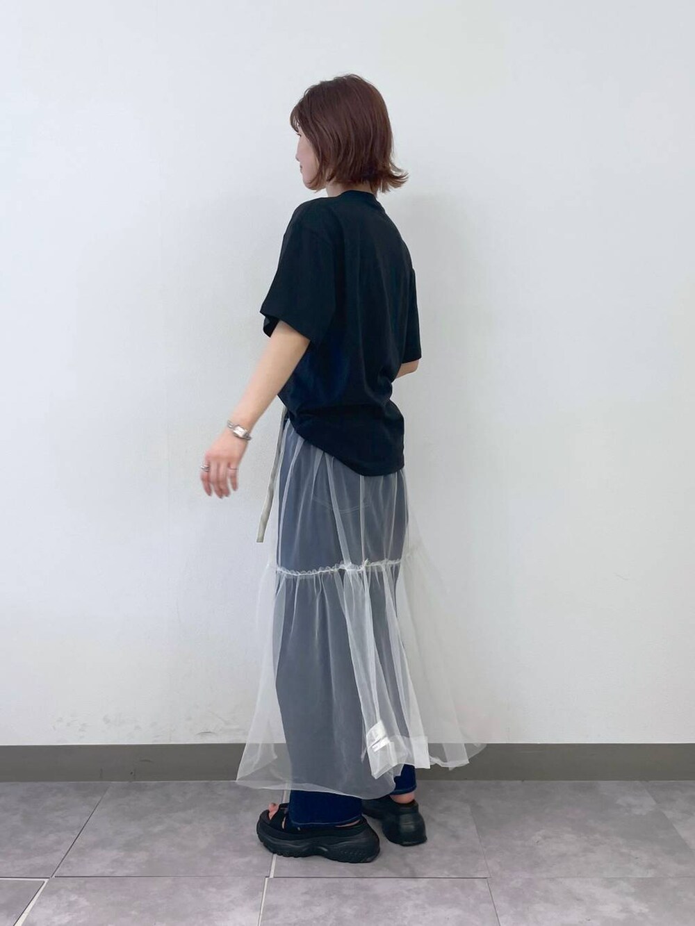 ブラック系のTシャツ/カットソー、ブルー系のデニムパンツ、ブラック系のサンダルを着用したレディースの夏コーディネートの4枚目の写真