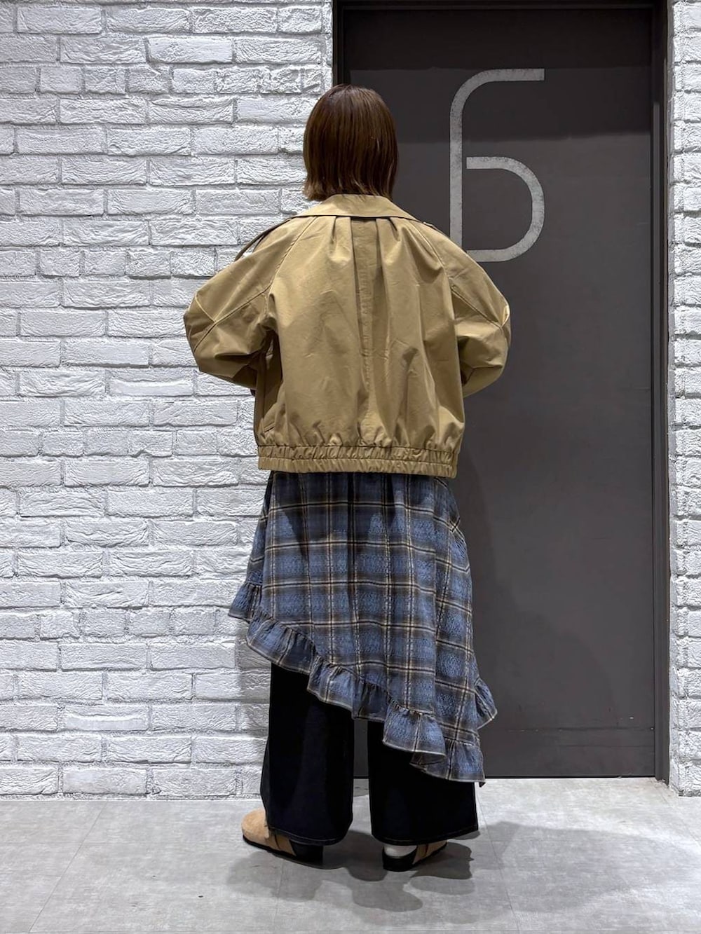 ブラック系のデニムパンツ、ベージュ系のトレンチコート、ブルー系のニット/セーターを着用したレディースの冬コーディネートの3枚目の写真