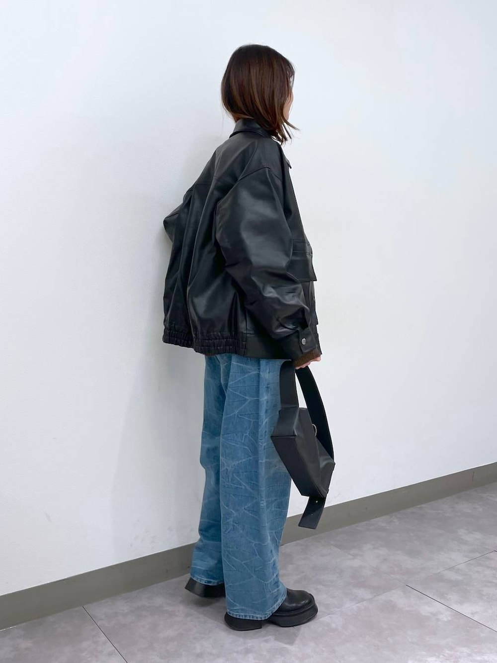 ブラック系のブーツ、ブラック系のショルダーバッグ、ブルー系のデニムパンツを着用したレディースの冬コーディネートの2枚目の写真