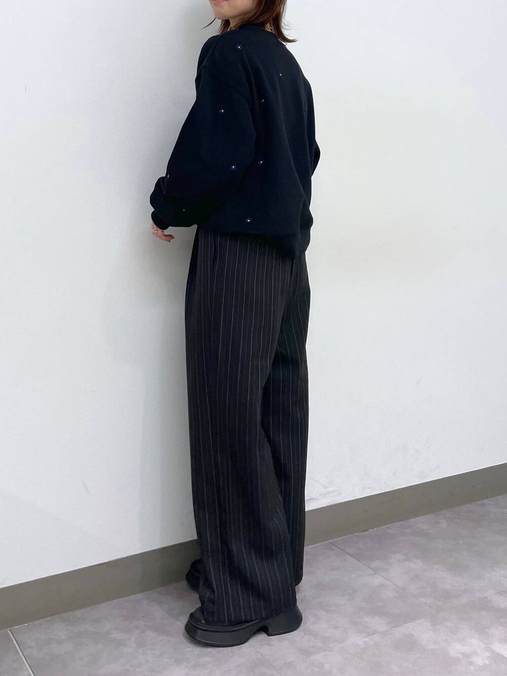 ブラック系のブーツ、ブラック系のスウェット、ブラック系のスラックスを着用したレディースの秋コーディネートの4枚目の写真