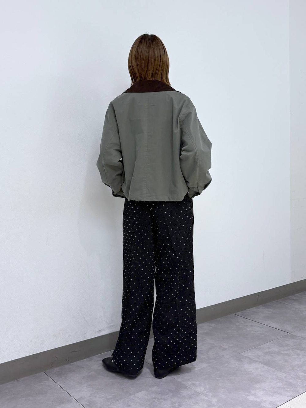 ブラック系のパンプス、ブラック系のスラックス、グリーン系のブルゾンを着用したレディースの春コーディネートの3枚目の写真