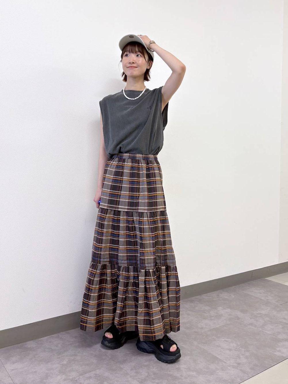 ブラック系のサンダル、ブラウン系のスカート、ブラック系のTシャツ/カットソーを着用したレディースの夏コーディネートの2枚目の写真