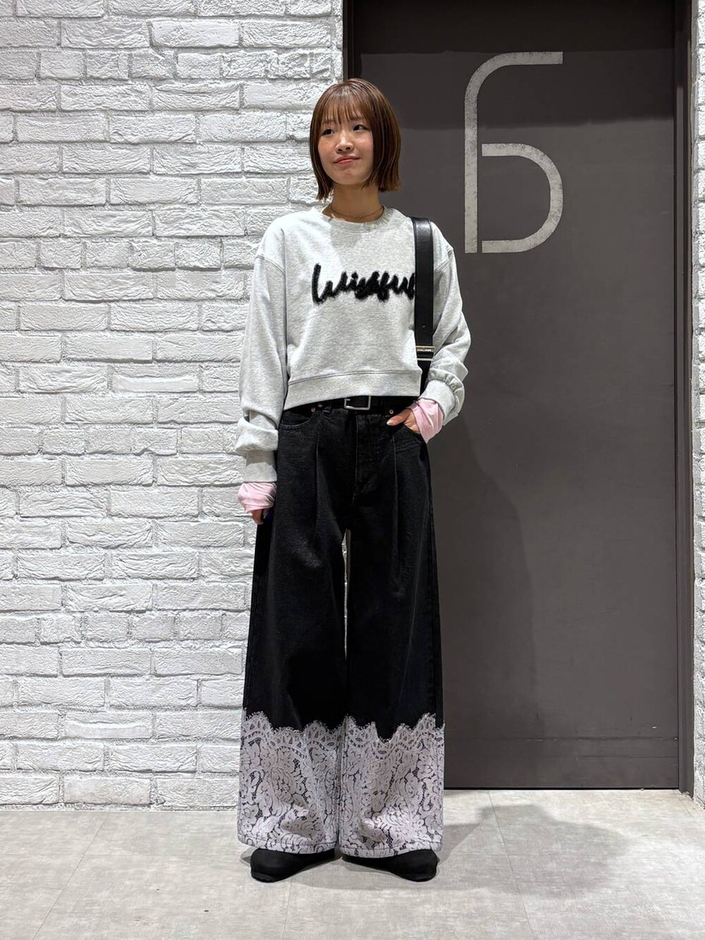 ブラック系のショルダーバッグ、ブラック系のデニムパンツ、グレー系のスウェットを着用したレディースの冬コーディネートの2枚目の写真