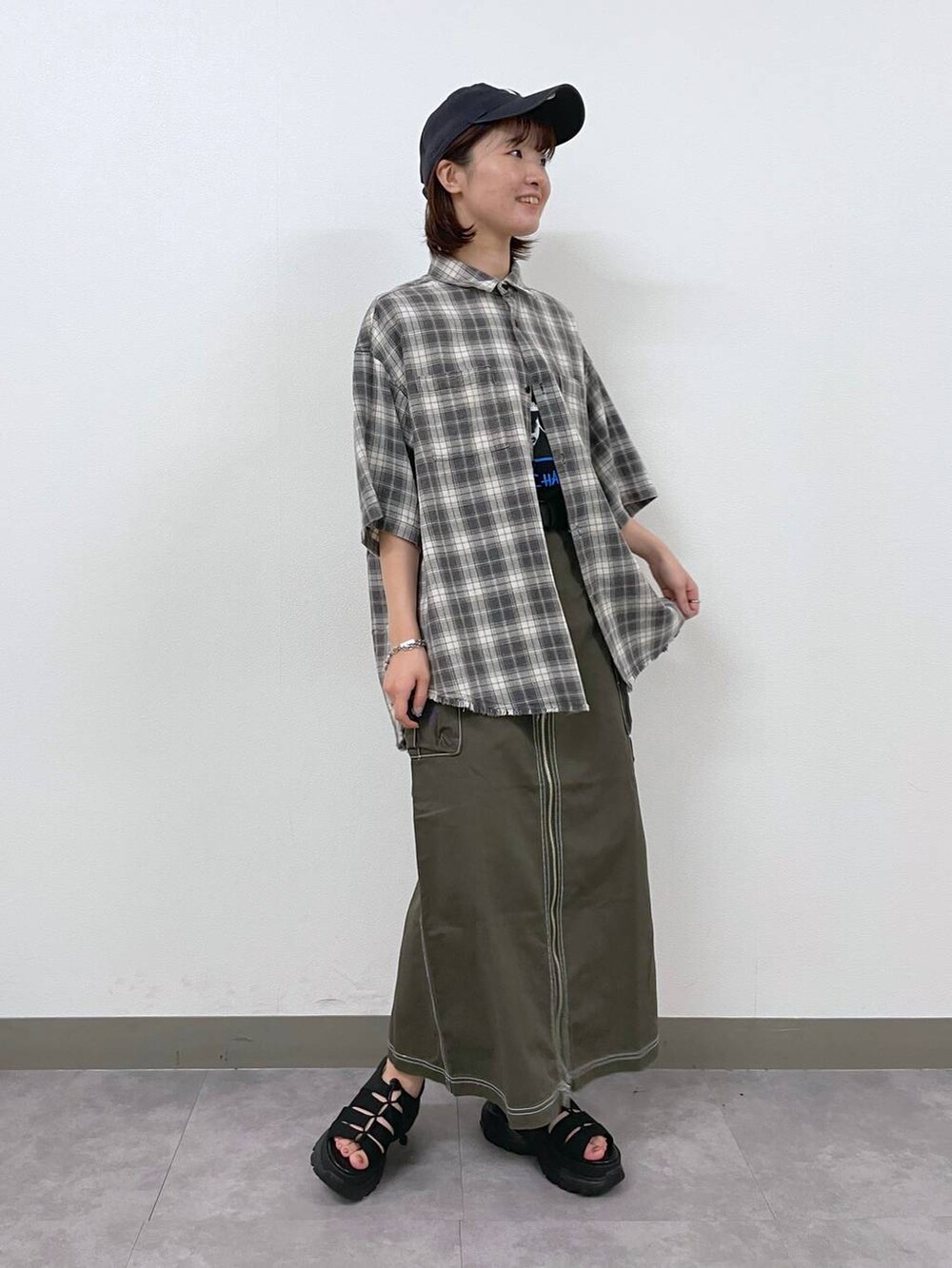 ブラック系のTシャツ/カットソー、ブラック系のサンダル、グリーン系のデニムスカートを着用したレディースの夏コーディネートの3枚目の写真