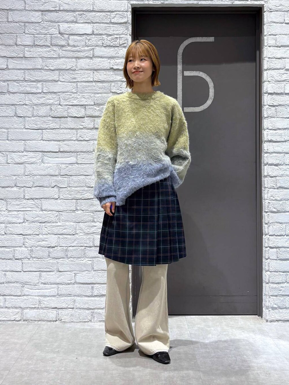 ホワイト系のデニムパンツ、グリーン系のスカート、イエロー系のニット/セーターを着用したレディースの秋コーディネートの2枚目の写真