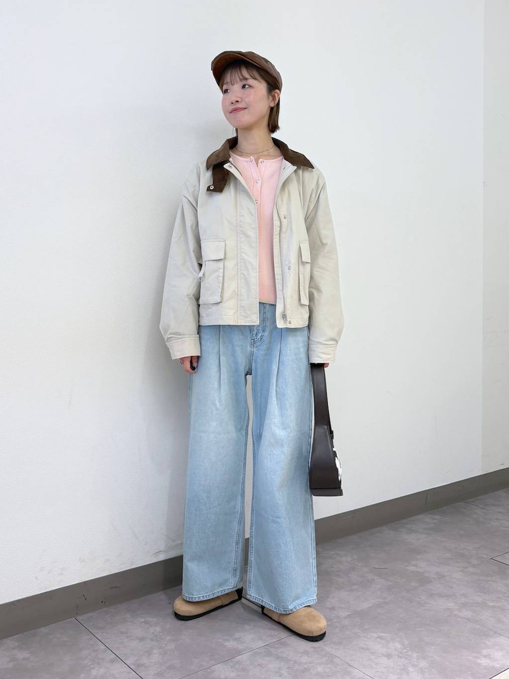 ブルー系のデニムパンツ、ピンク系のカーディガン/ボレロ、ブラウン系のショルダーバッグを着用したレディースの冬コーディネートの5枚目の写真