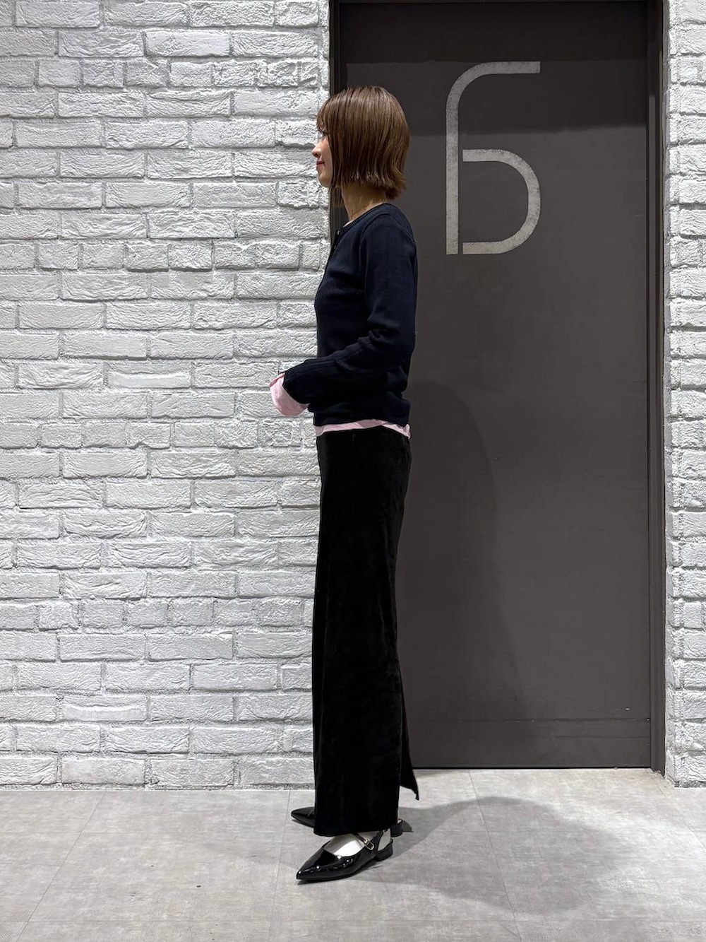 ブラック系のスカート、ブラック系のパンプス、ピンク系のTシャツ/カットソーを着用したレディースの冬コーディネートの3枚目の写真