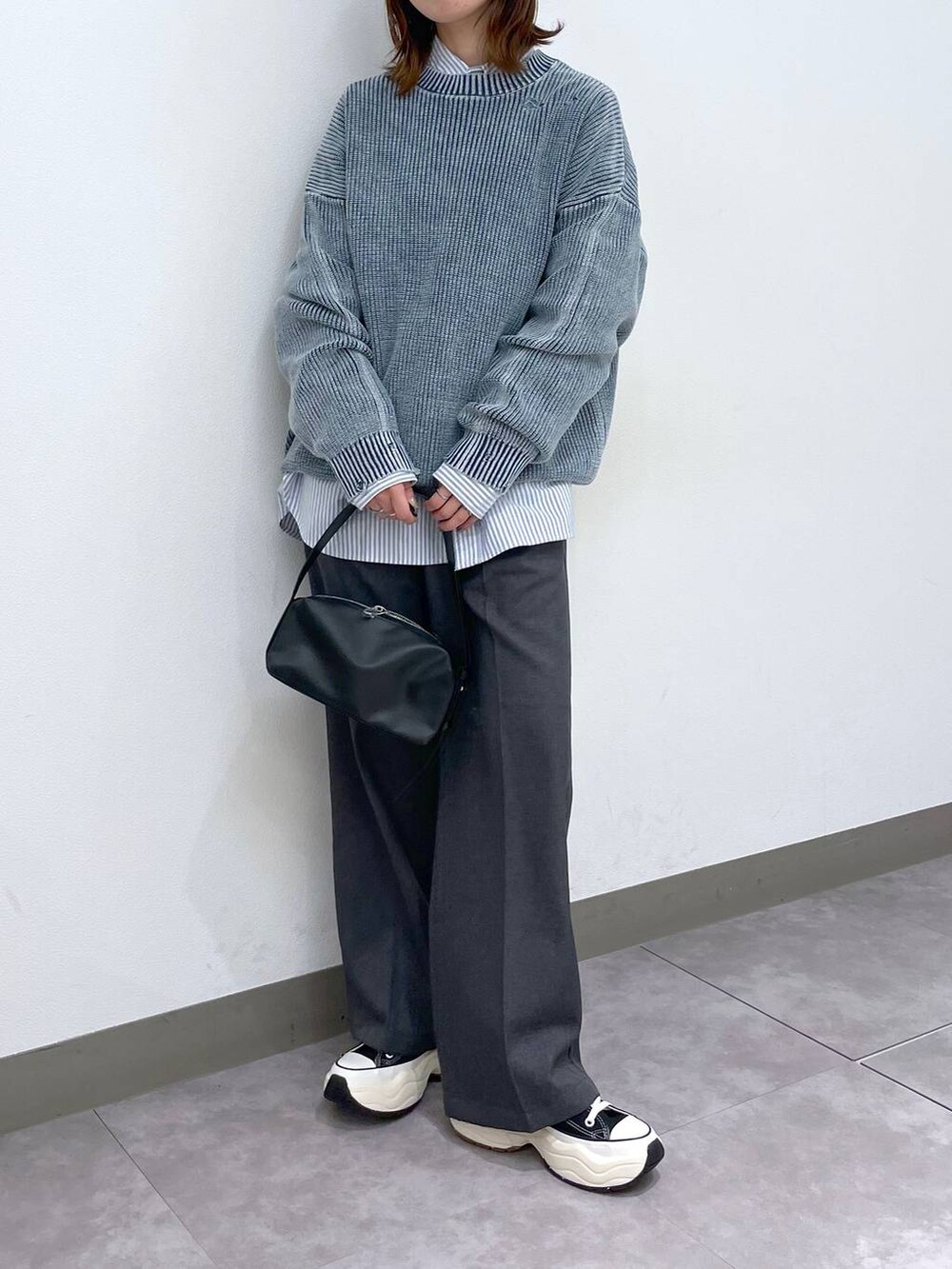 グレー系のスラックス、ブラック系のスニーカー、ブラック系のショルダーバッグを着用したレディースの冬コーディネートの3枚目の写真