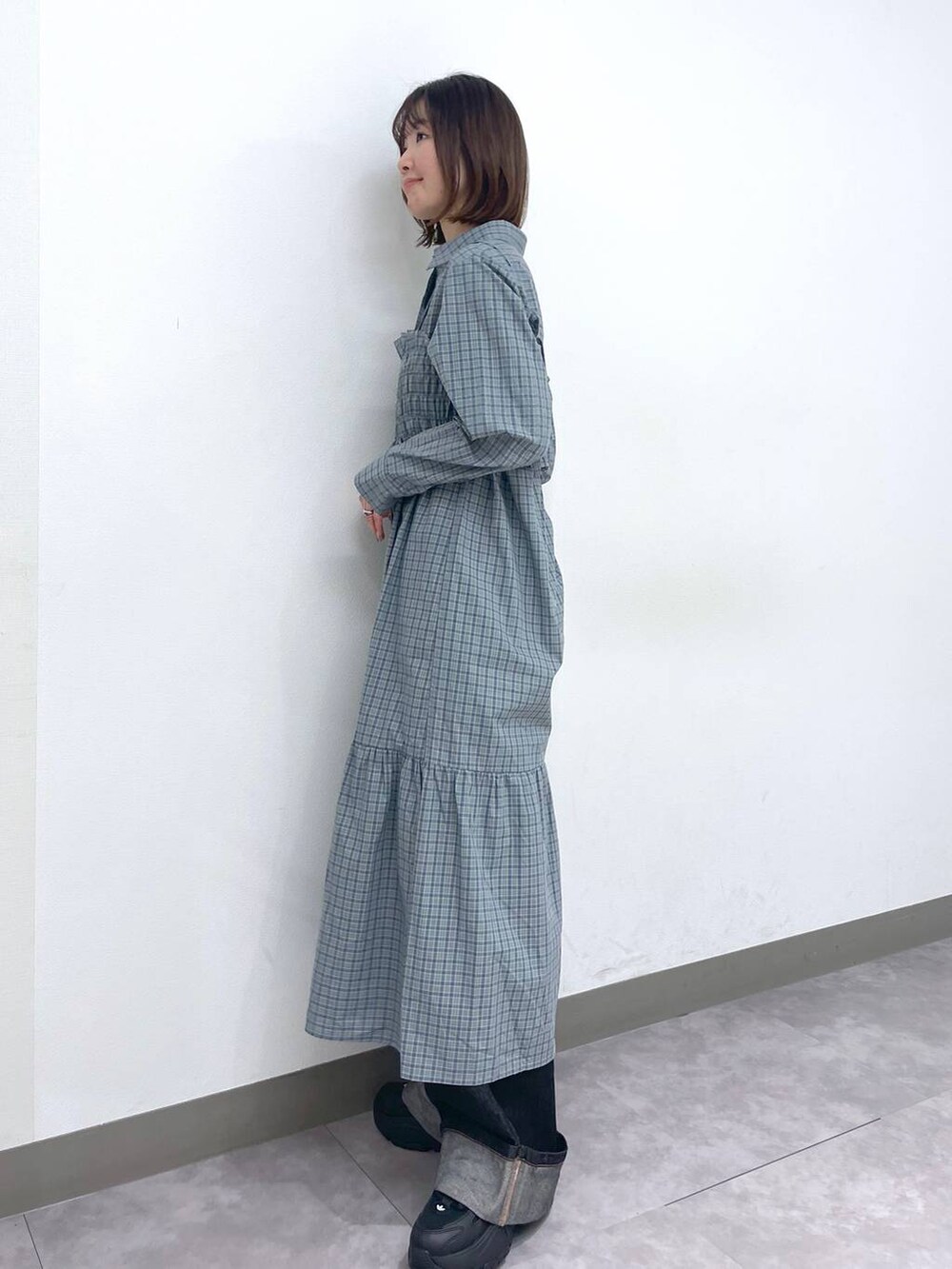 ブラック系のスニーカー、ブルー系のシャツワンピース、ブラック系のデニムパンツを着用したレディースの春コーディネートの5枚目の写真