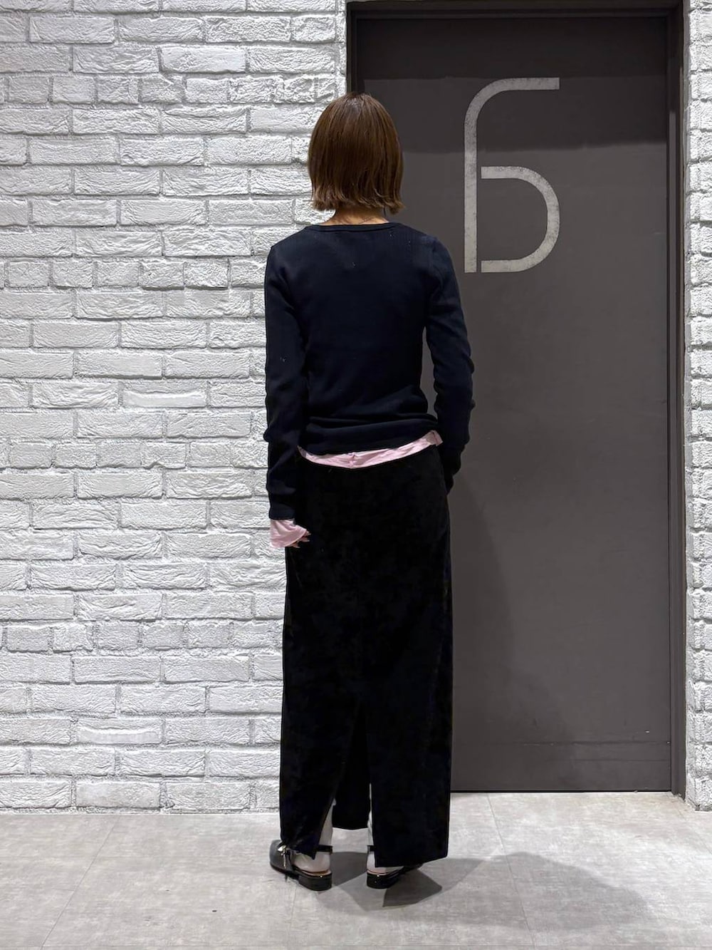 ブラック系のスカート、ブラック系のパンプス、ピンク系のTシャツ/カットソーを着用したレディースの冬コーディネートの4枚目の写真