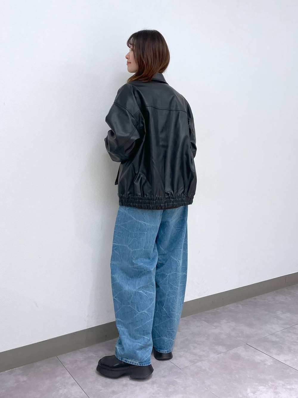 ブラック系のブーツ、ブラック系のショルダーバッグ、ブルー系のデニムパンツを着用したレディースの冬コーディネートの3枚目の写真