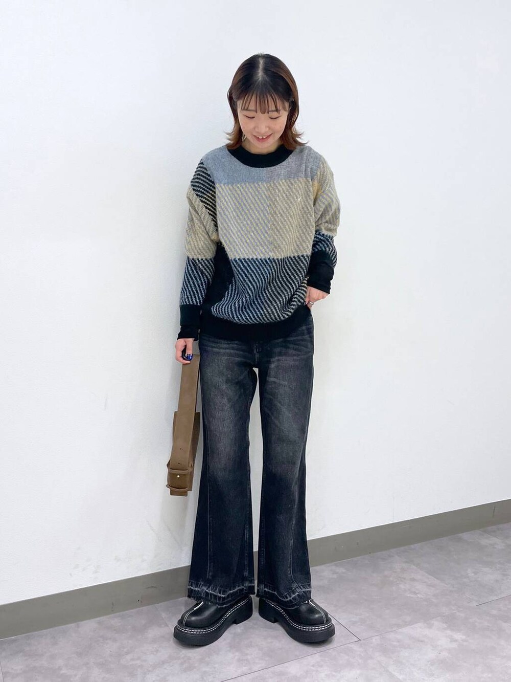 ブラック系のローファー、グレー系のニット/セーター、ブラック系のデニムパンツを着用したレディースの秋コーディネートの2枚目の写真