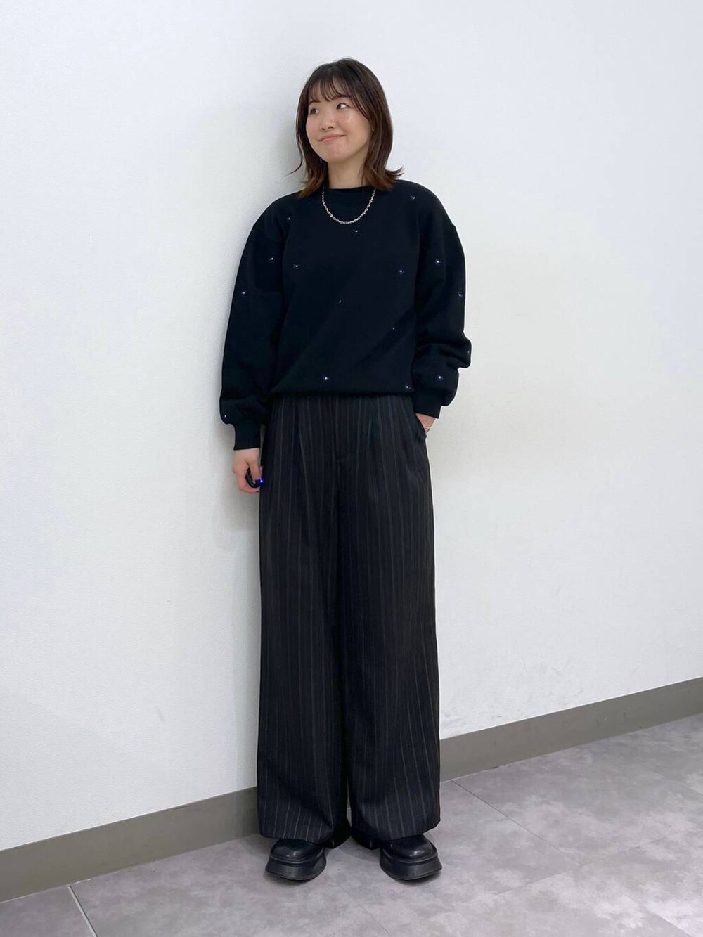 ブラック系のブーツ、ブラック系のスウェット、ブラック系のスラックスを着用したレディースの秋コーディネートの6枚目の写真