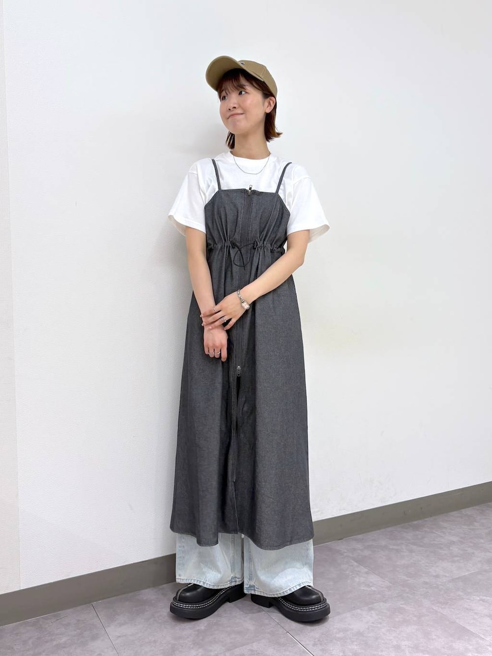 ブラック系のローファー、ブルー系のデニムパンツ、グレー系のワンピースを着用したレディースの春コーディネートの2枚目の写真