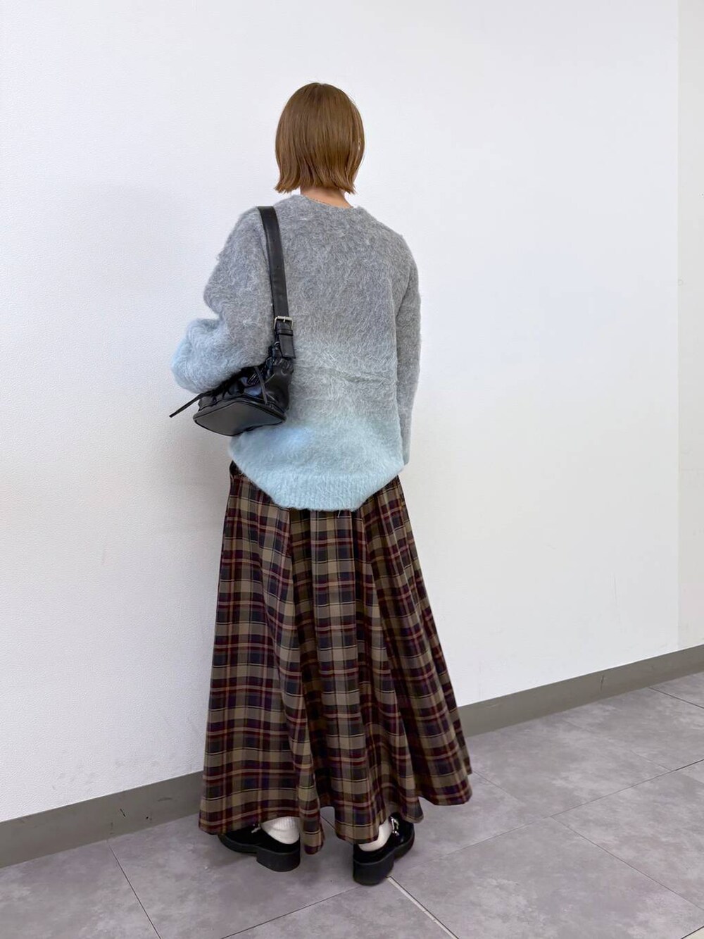 ブラック系のショルダーバッグ、レッド系のスカート、グレー系のニット/セーターを着用したレディースの秋コーディネートの3枚目の写真