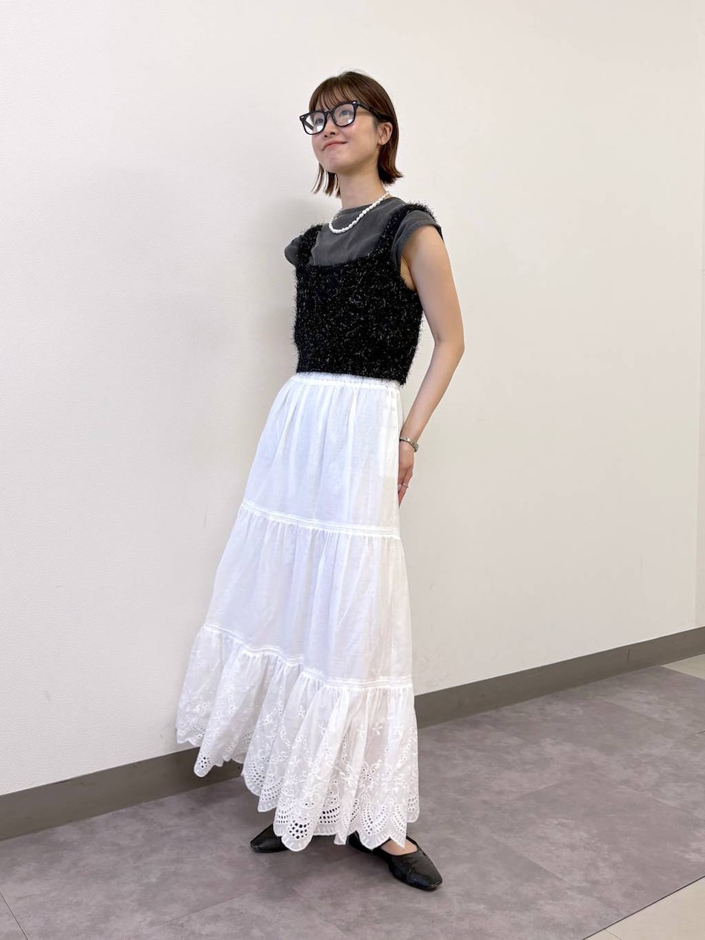 ブラック系のベスト、ブラック系のTシャツ/カットソー、ホワイト系のスカートを着用したレディースの夏コーディネートの3枚目の写真