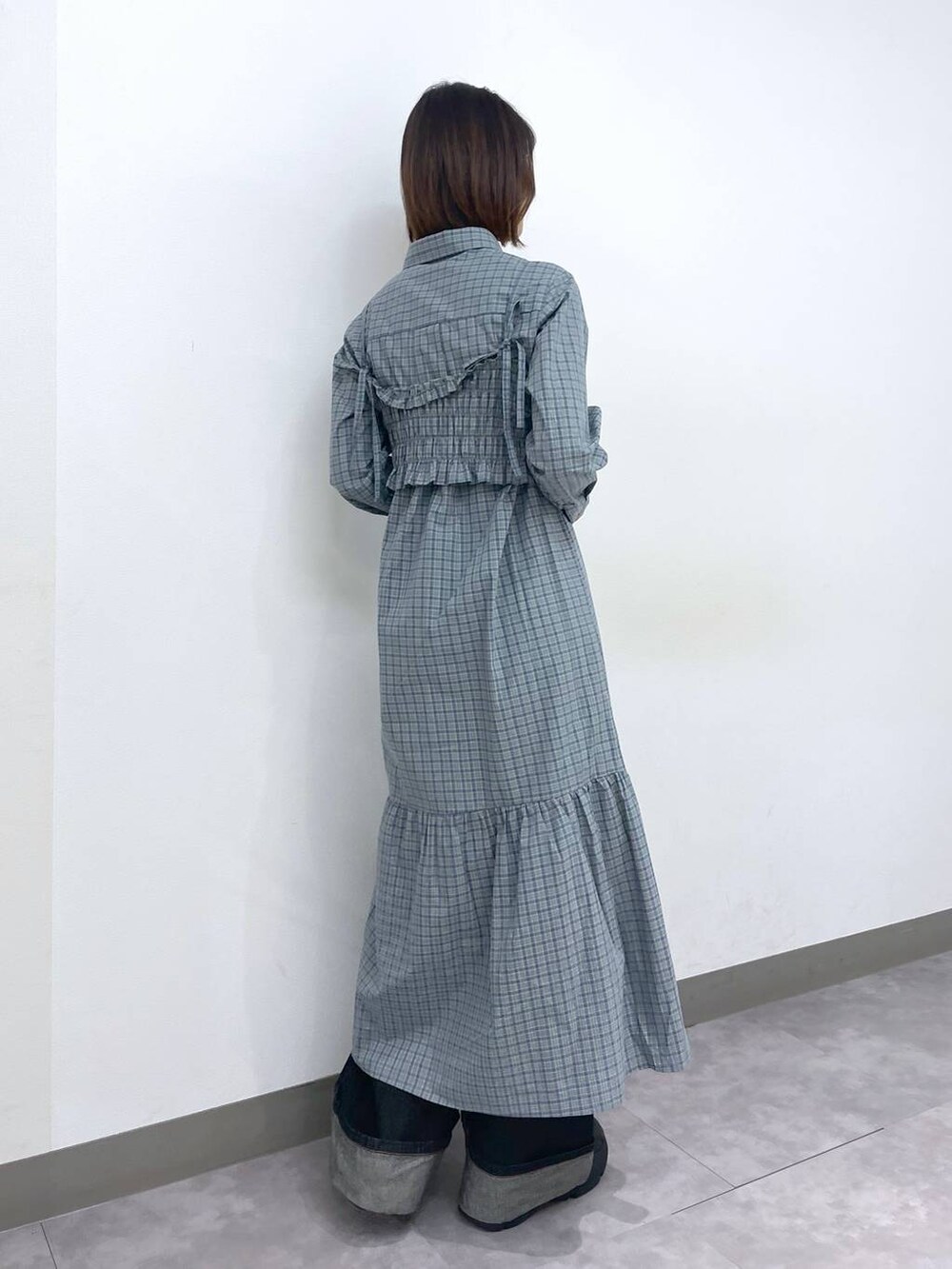 ブラック系のスニーカー、ブルー系のシャツワンピース、ブラック系のデニムパンツを着用したレディースの春コーディネートの4枚目の写真