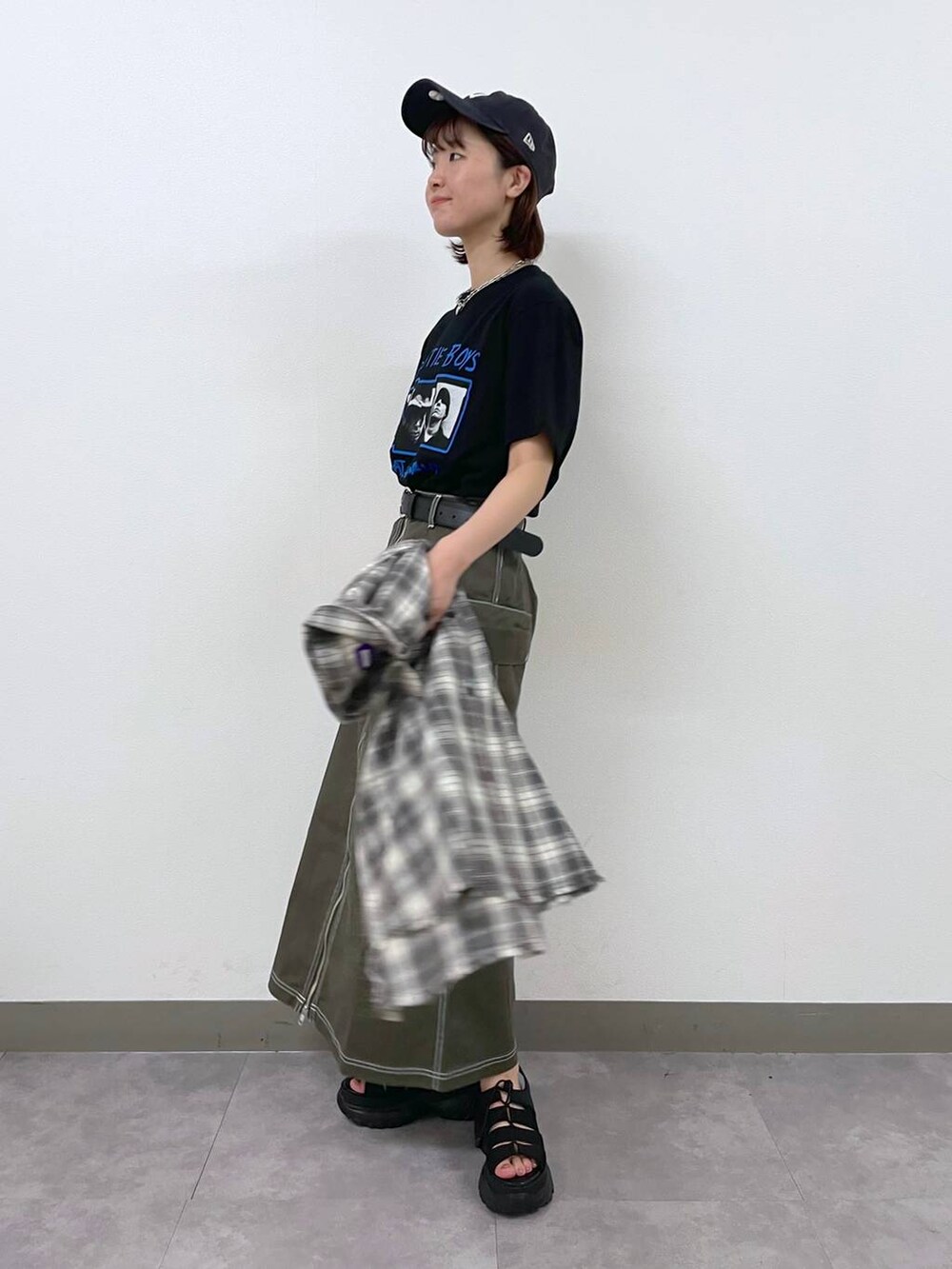 ブラック系のTシャツ/カットソー、ブラック系のサンダル、グリーン系のデニムスカートを着用したレディースの夏コーディネートの2枚目の写真