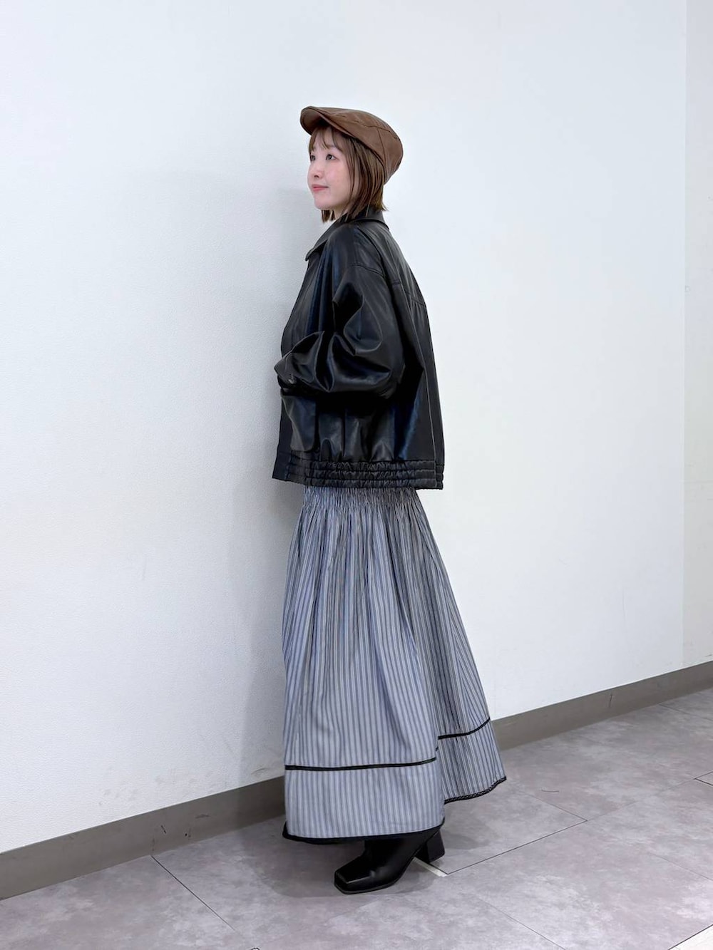 グレー系のスカート、ブラック系のブルゾン、ブルー系のニット/セーターを着用したレディースの冬コーディネートの2枚目の写真