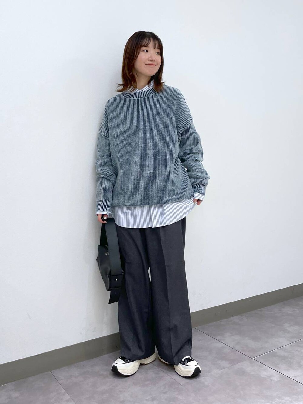 グレー系のスラックス、ブラック系のスニーカー、ブラック系のショルダーバッグを着用したレディースの冬コーディネートの2枚目の写真