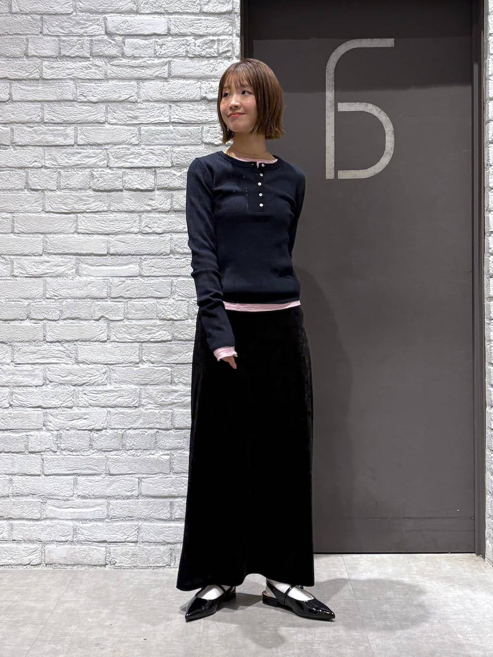 ブラック系のスカート、ブラック系のパンプス、ピンク系のTシャツ/カットソーを着用したレディースの冬コーディネートの7枚目の写真