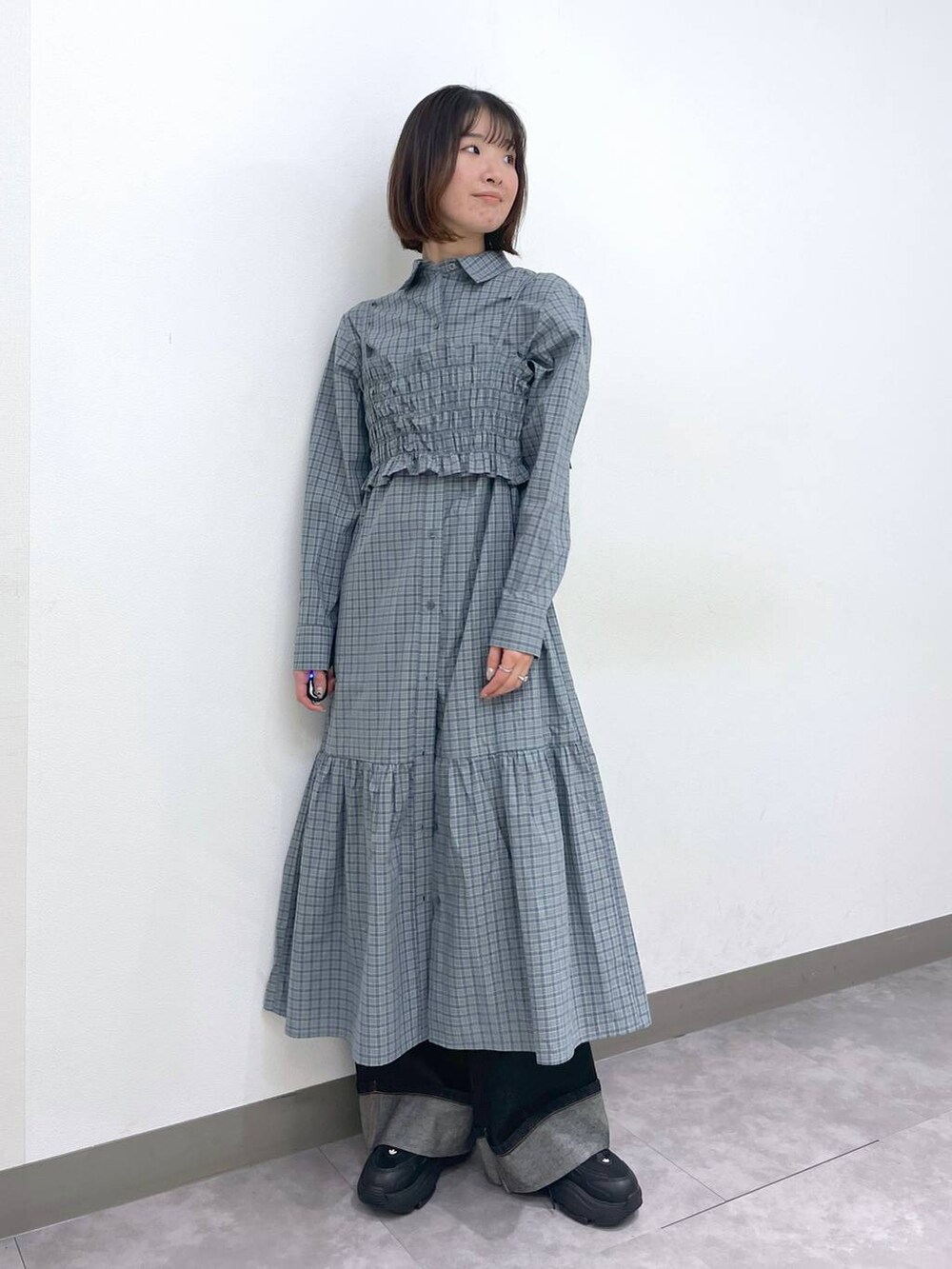 ブラック系のスニーカー、ブルー系のシャツワンピース、ブラック系のデニムパンツを着用したレディースの春コーディネートの2枚目の写真