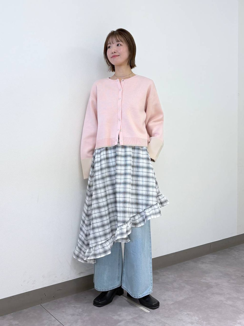 ブルー系のデニムパンツ、ピンク系のカーディガン/ボレロ、ブラック系のブーツを着用したレディースの冬コーディネートの2枚目の写真