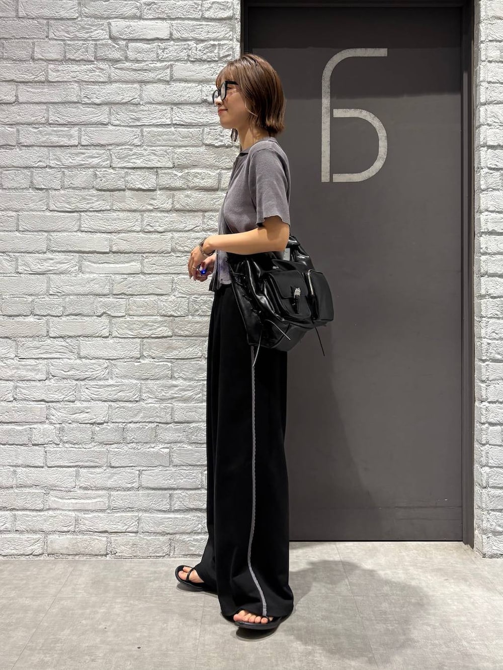 グレー系のニット/セーター、ブラック系のスウェットパンツ、ブラック系のショルダーバッグを着用したレディースの夏コーディネートの3枚目の写真