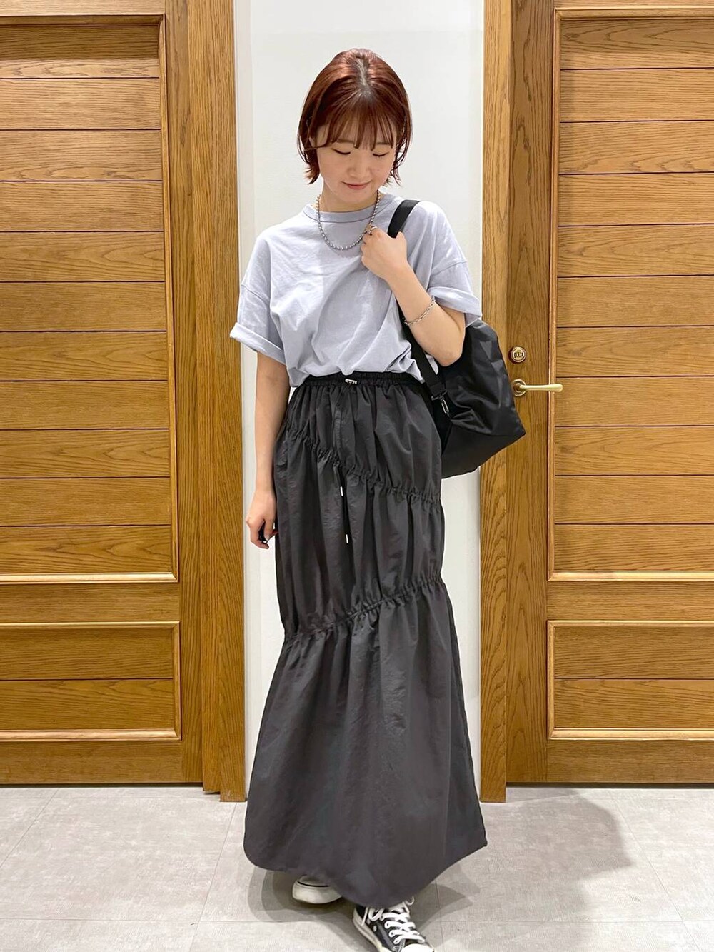 ブラック系のショルダーバッグ、ブルー系のTシャツ/カットソー、グレー系のスカートを着用したレディースの夏コーディネートの2枚目の写真