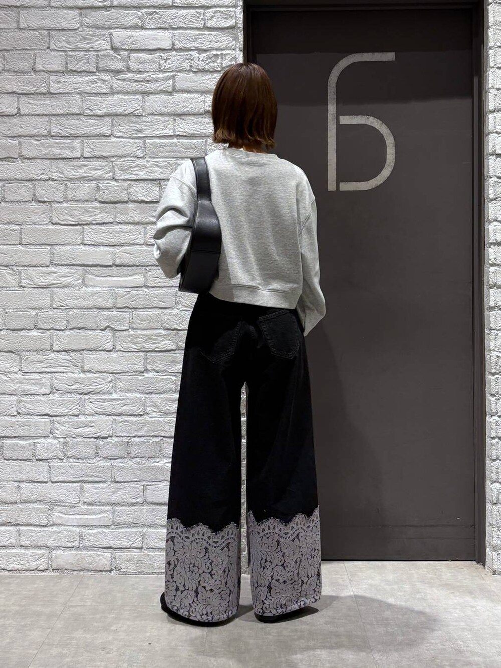 ブラック系のショルダーバッグ、ブラック系のデニムパンツ、グレー系のスウェットを着用したレディースの冬コーディネートの4枚目の写真