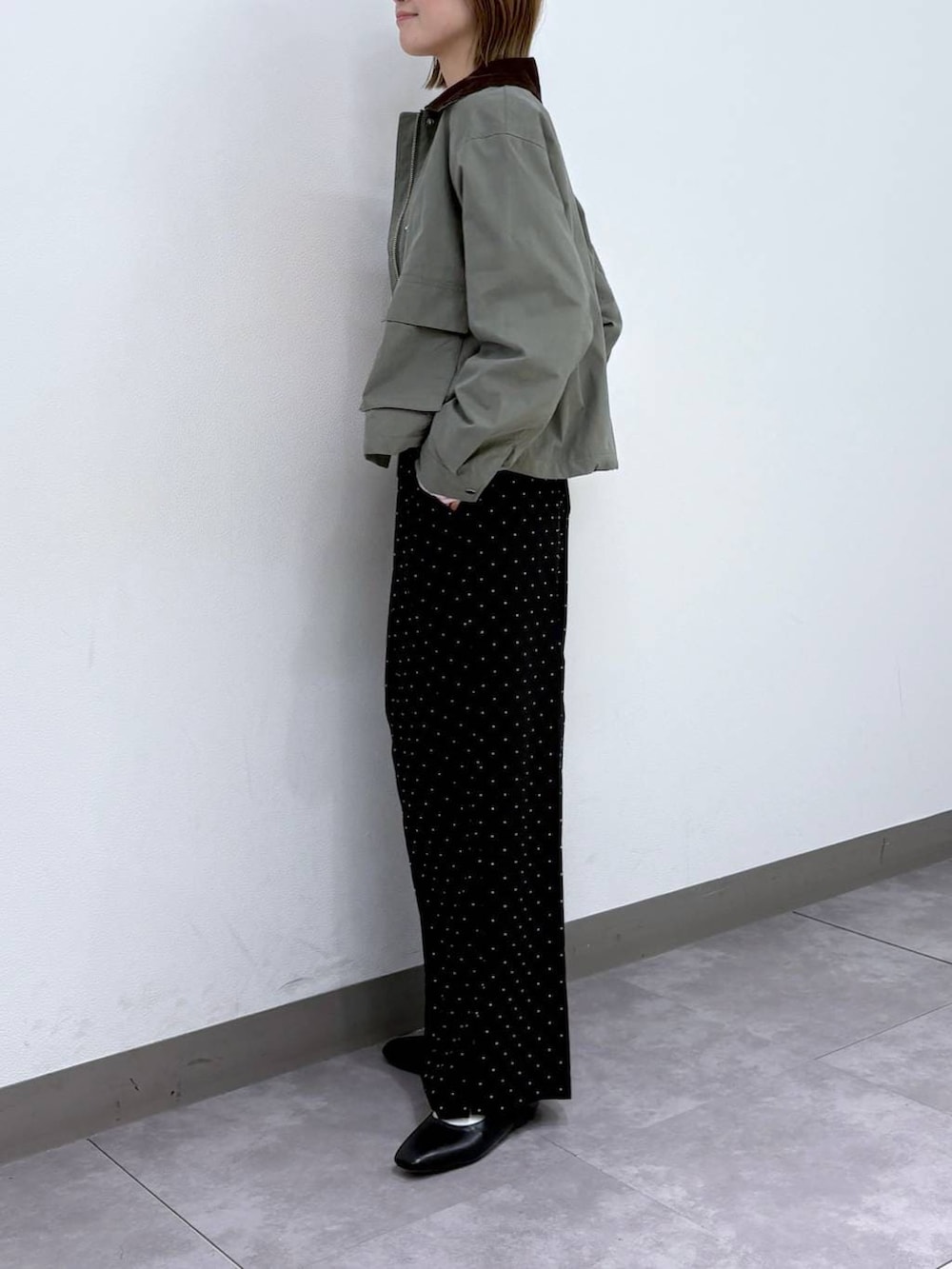ブラック系のパンプス、ブラック系のスラックス、グリーン系のブルゾンを着用したレディースの春コーディネートの2枚目の写真