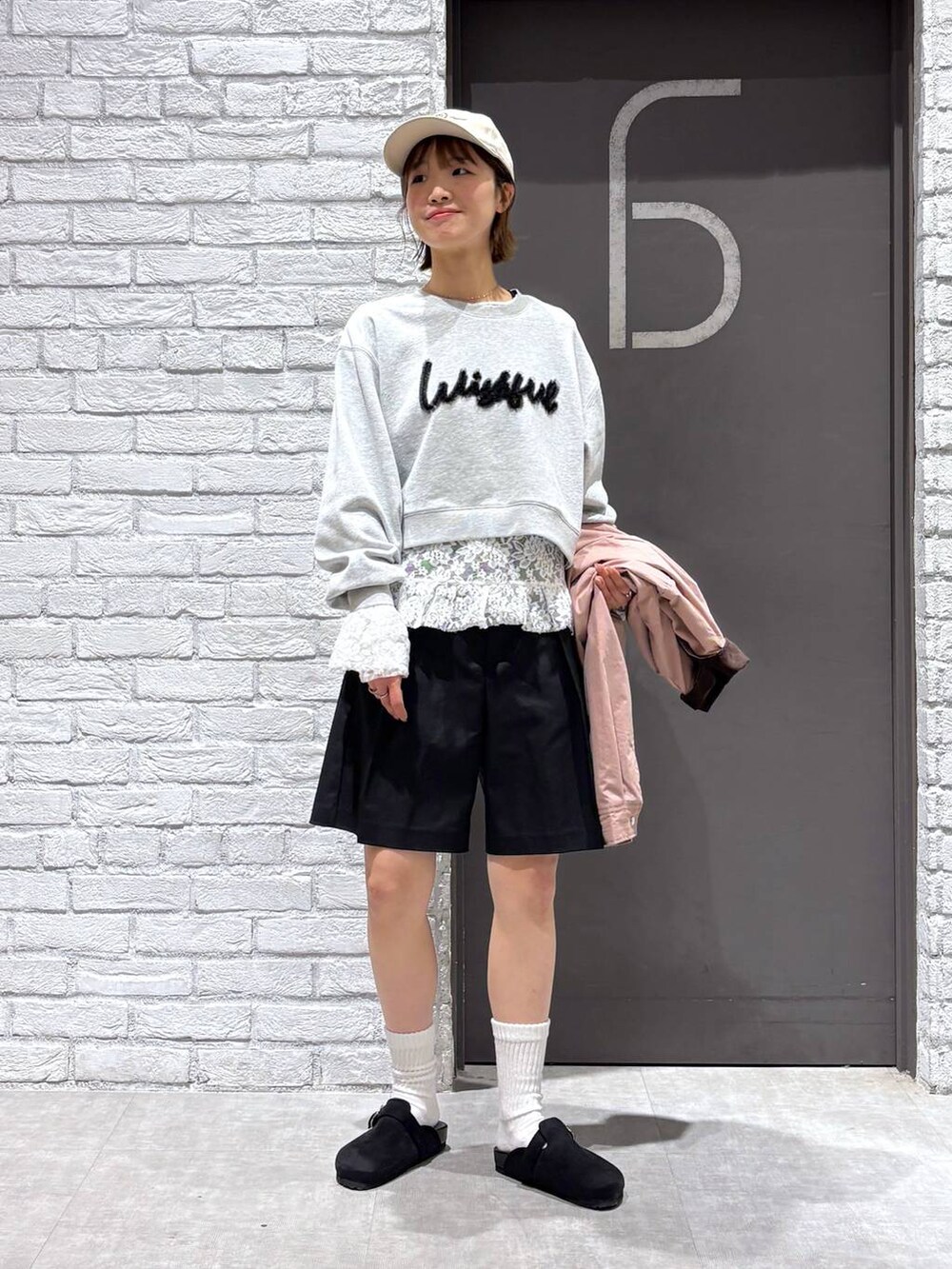 ブラック系のスラックス、ピンク系のブルゾン、グレー系のスウェットを着用したレディースの冬コーディネートの2枚目の写真