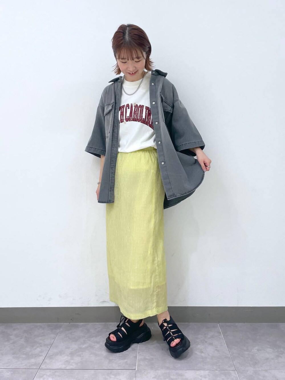 イエロー系のスカート、グレー系のシャツ/ブラウス、ブラック系のサンダルを着用したレディースの夏コーディネートの3枚目の写真