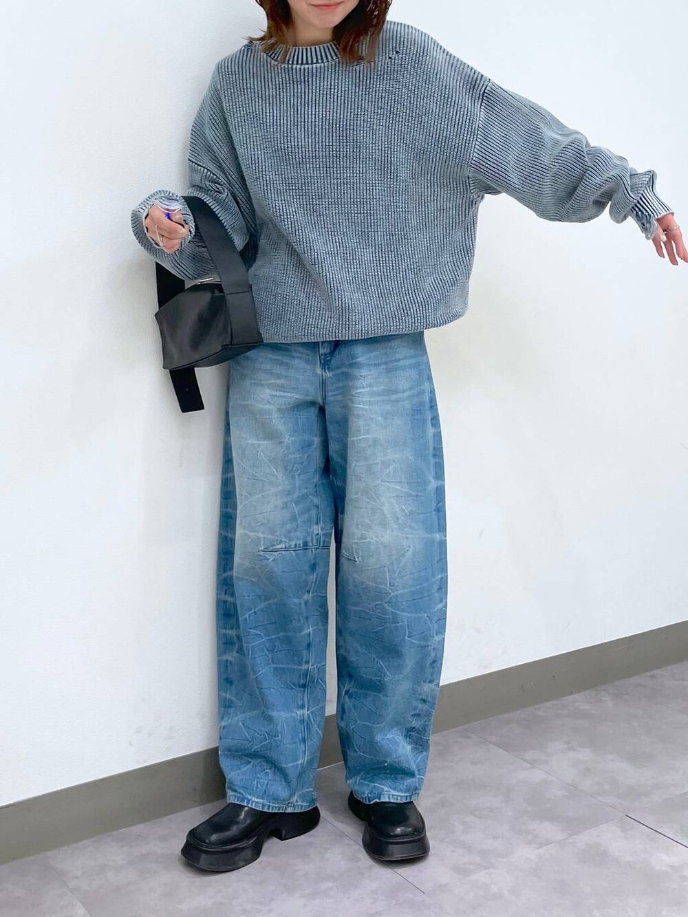 ブラック系のブーツ、ブラック系のショルダーバッグ、ブルー系のデニムパンツを着用したレディースの冬コーディネートの2枚目の写真