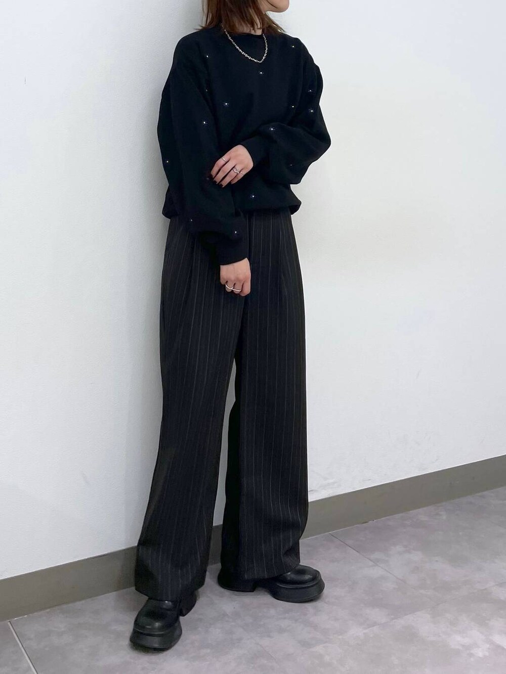 ブラック系のブーツ、ブラック系のスウェット、ブラック系のスラックスを着用したレディースの秋コーディネートの3枚目の写真