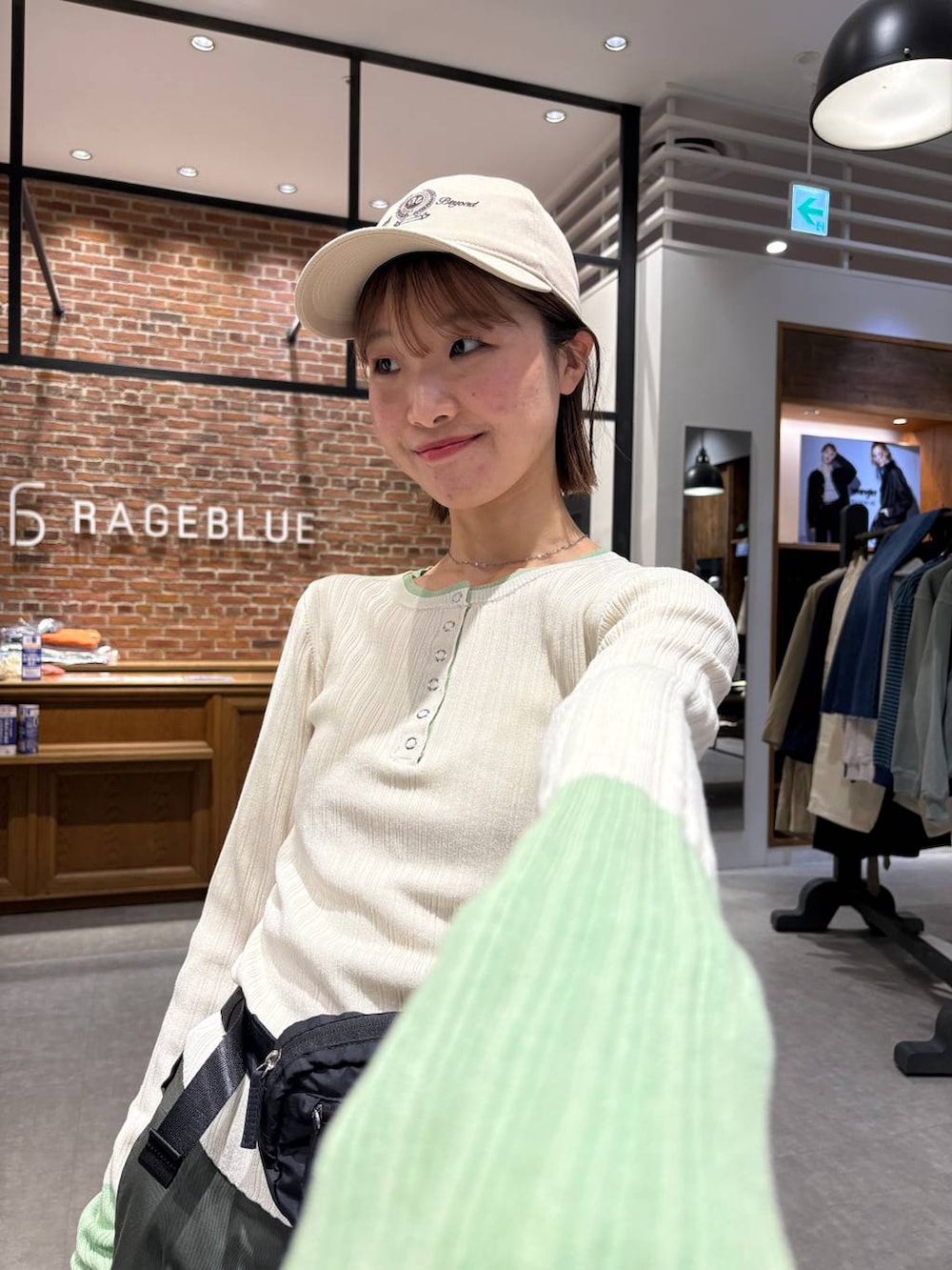 ブラック系のボディバッグ/ウエストポーチ、ホワイト系のニット/セーター、ベージュ系のキャップを着用したレディースの春コーディネートの5枚目の写真