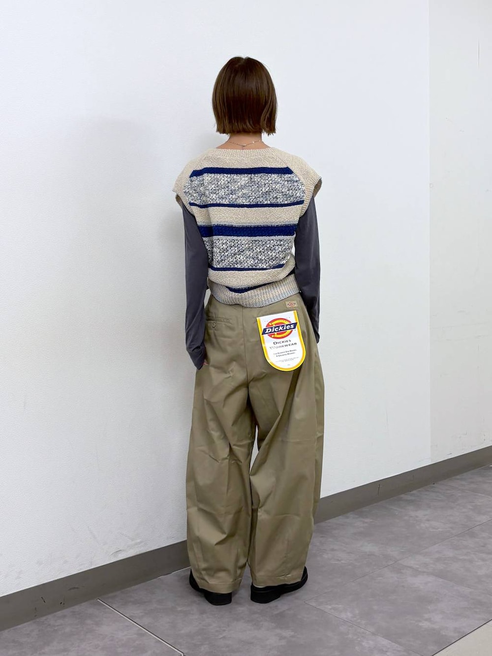 ベージュ系のチノパンツ、ブラック系のボディバッグ/ウエストポーチ、ブルー系のベストを着用したレディースの春コーディネートの4枚目の写真