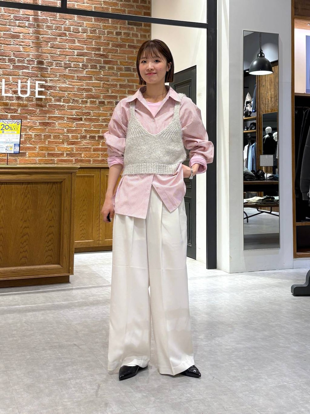 グレー系のニット/セーター、ブラック系のパンプス、ピンク系のシャツ/ブラウスを着用したレディースの春コーディネートの4枚目の写真