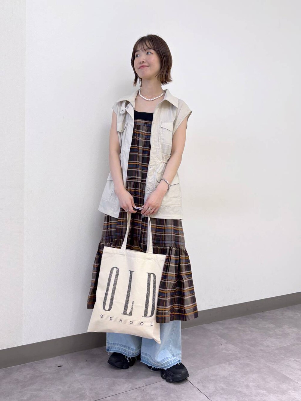 ブラック系のサンダル、ブルー系のデニムパンツ、ホワイト系のベストを着用したレディースの夏コーディネートの2枚目の写真