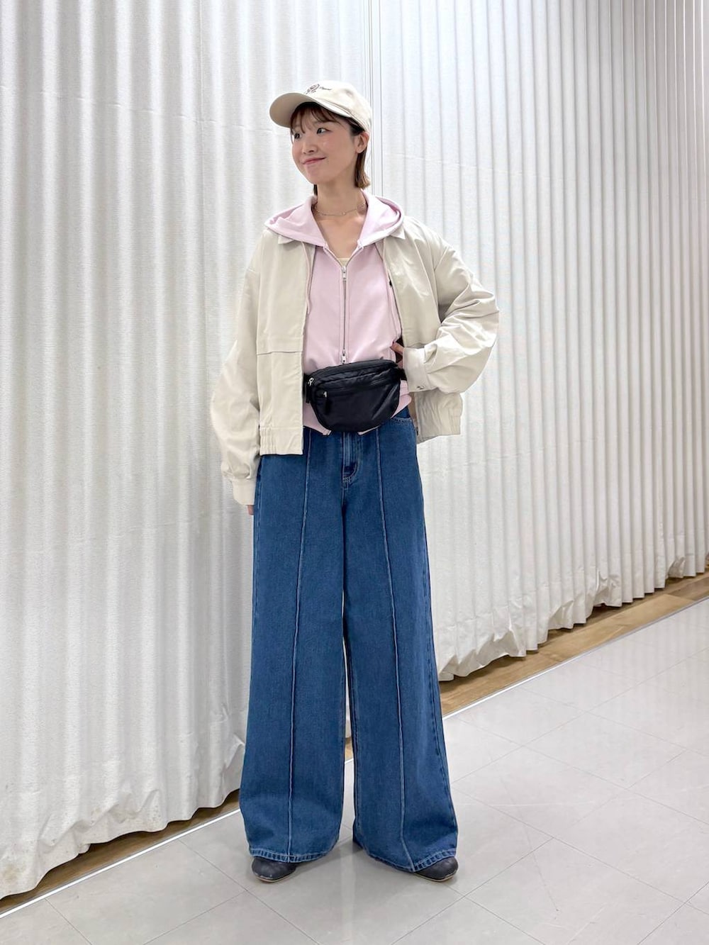 ブラック系のボディバッグ/ウエストポーチ、ブルー系のデニムパンツ、ベージュ系のブルゾンを着用したレディースの春コーディネートの6枚目の写真