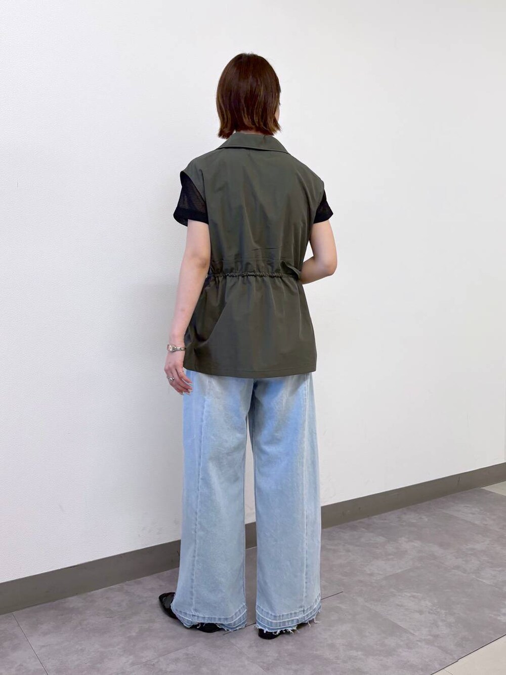 ブラック系のTシャツ/カットソー、ブルー系のデニムパンツ、グリーン系のベストを着用したレディースの夏コーディネートの4枚目の写真