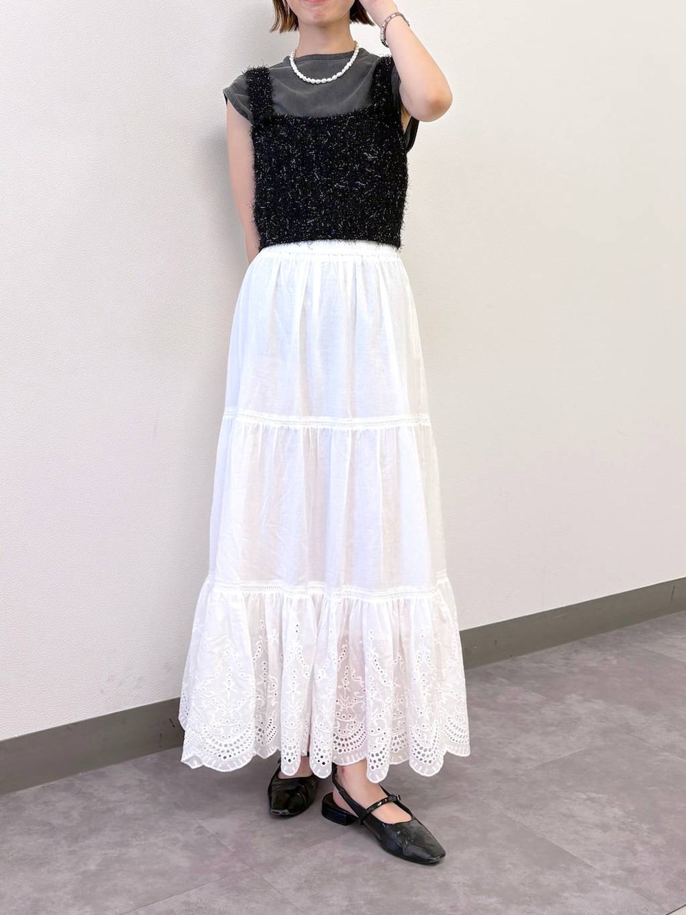 ブラック系のベスト、ブラック系のTシャツ/カットソー、ホワイト系のスカートを着用したレディースの夏コーディネートの2枚目の写真
