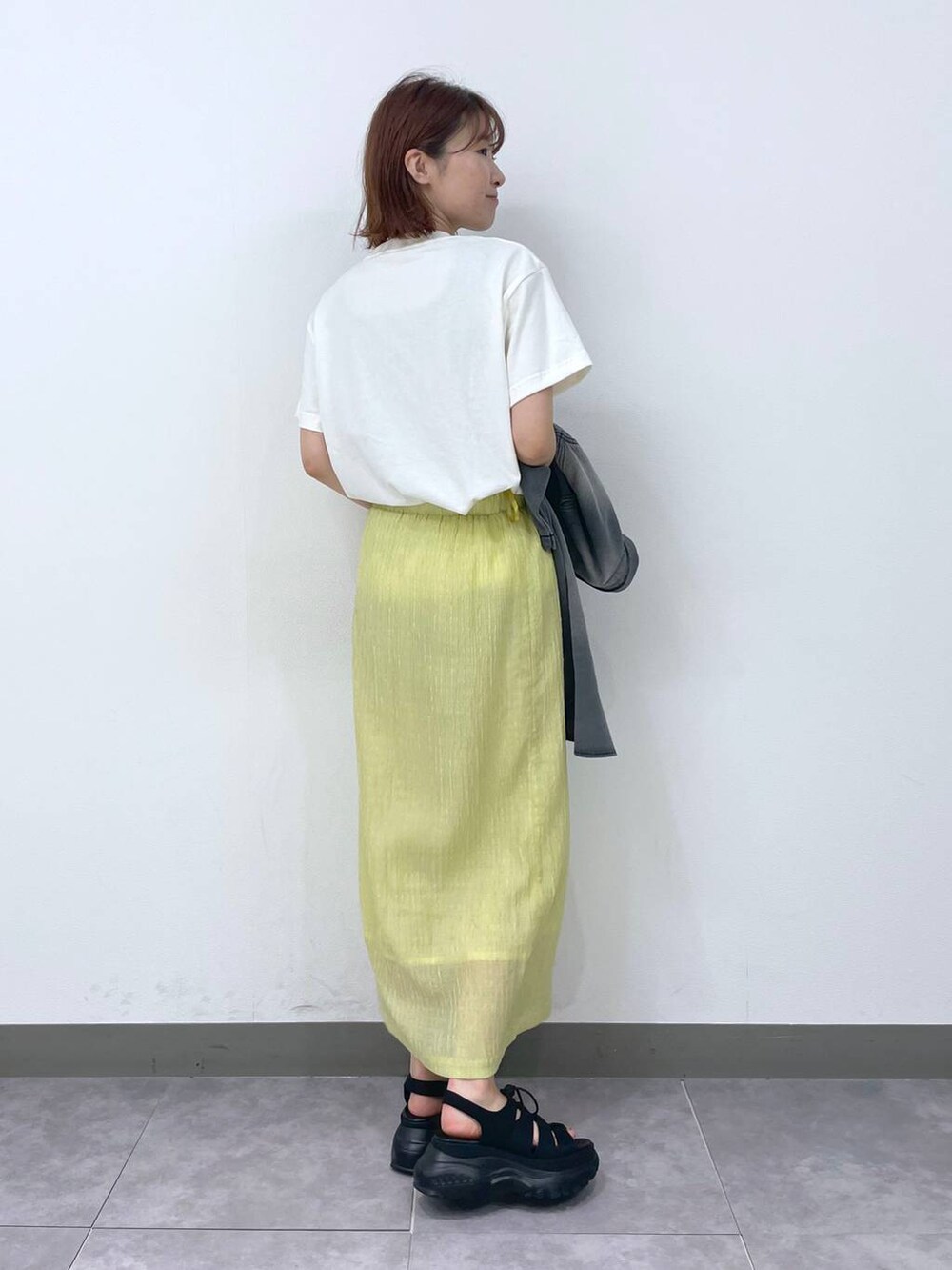 イエロー系のスカート、グレー系のシャツ/ブラウス、ブラック系のサンダルを着用したレディースの夏コーディネートの4枚目の写真