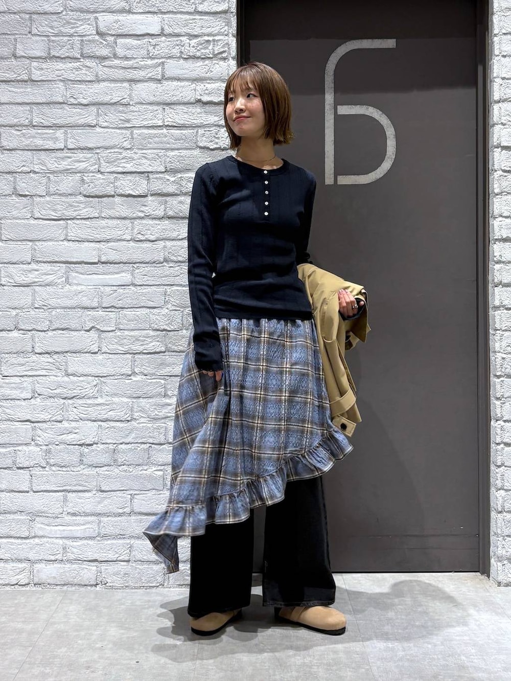 ブラック系のデニムパンツ、ベージュ系のトレンチコート、ブルー系のニット/セーターを着用したレディースの冬コーディネートの5枚目の写真